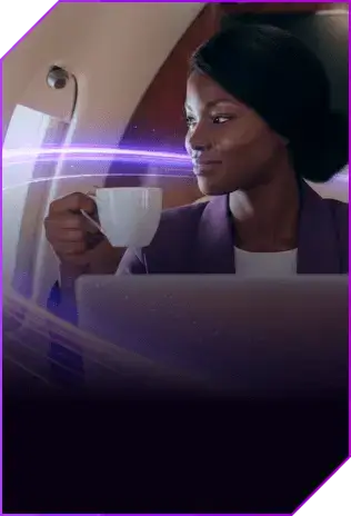 Mulher negra sorrindo segurando uma xícara em frente ao notebook