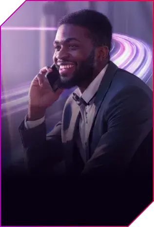 Homem negro de barba sorrindo e falando ao celular